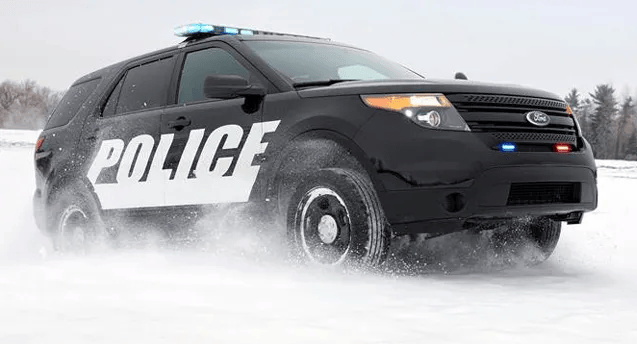 Police car patrolling snowy roads to enforce snow laws